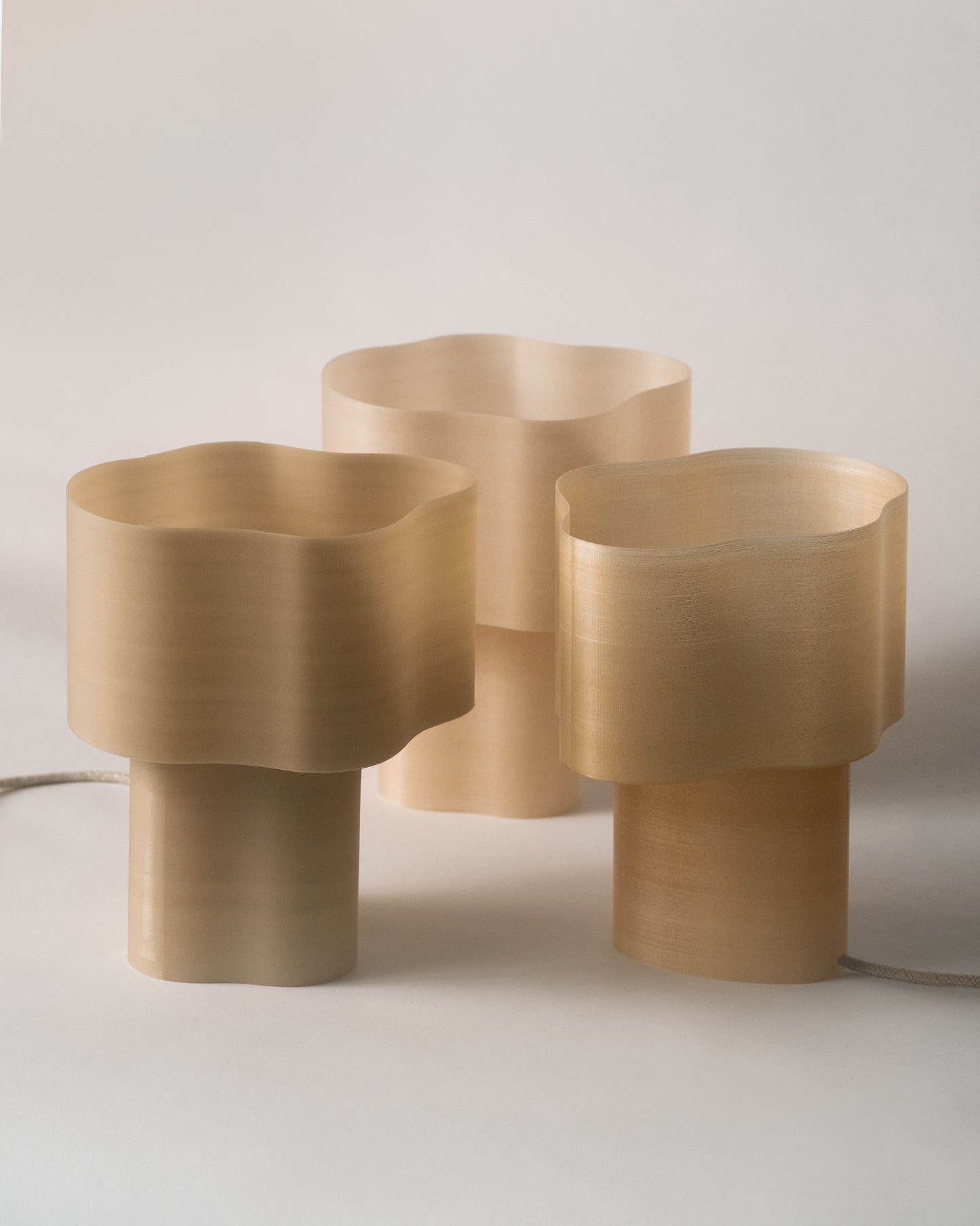 Collection of Cloudy Lamps in various earthy colors, 3D-printed from PLA filaments mixed with natural by-products like mussel shells, oysters, scallops, and wheat offcuts. Eco-friendly, with unique textures and colors created through recycling waste from agriculture and catering. Provides ambient, decorative light.