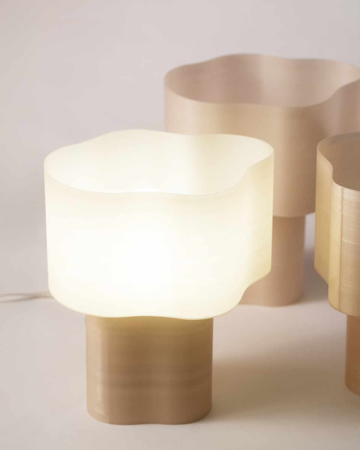 Collection of Cloudy Lamps in various earthy colors, 3D-printed from PLA filaments mixed with natural by-products like mussel shells, oysters, scallops, and wheat offcuts. Eco-friendly, with unique textures and colors created through recycling waste from agriculture and catering. Provides ambient, decorative light.